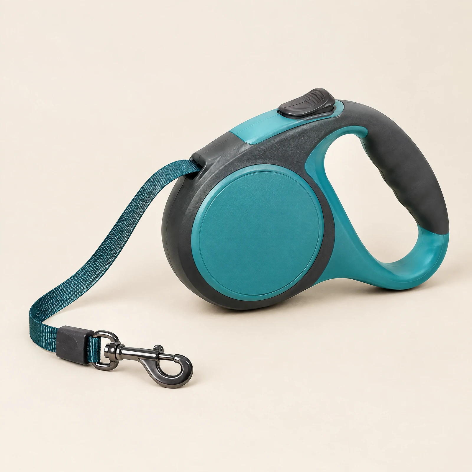A teal and charcoal retractable dog leash with a molded handle and a partly extended flat tape cord, on a cream background